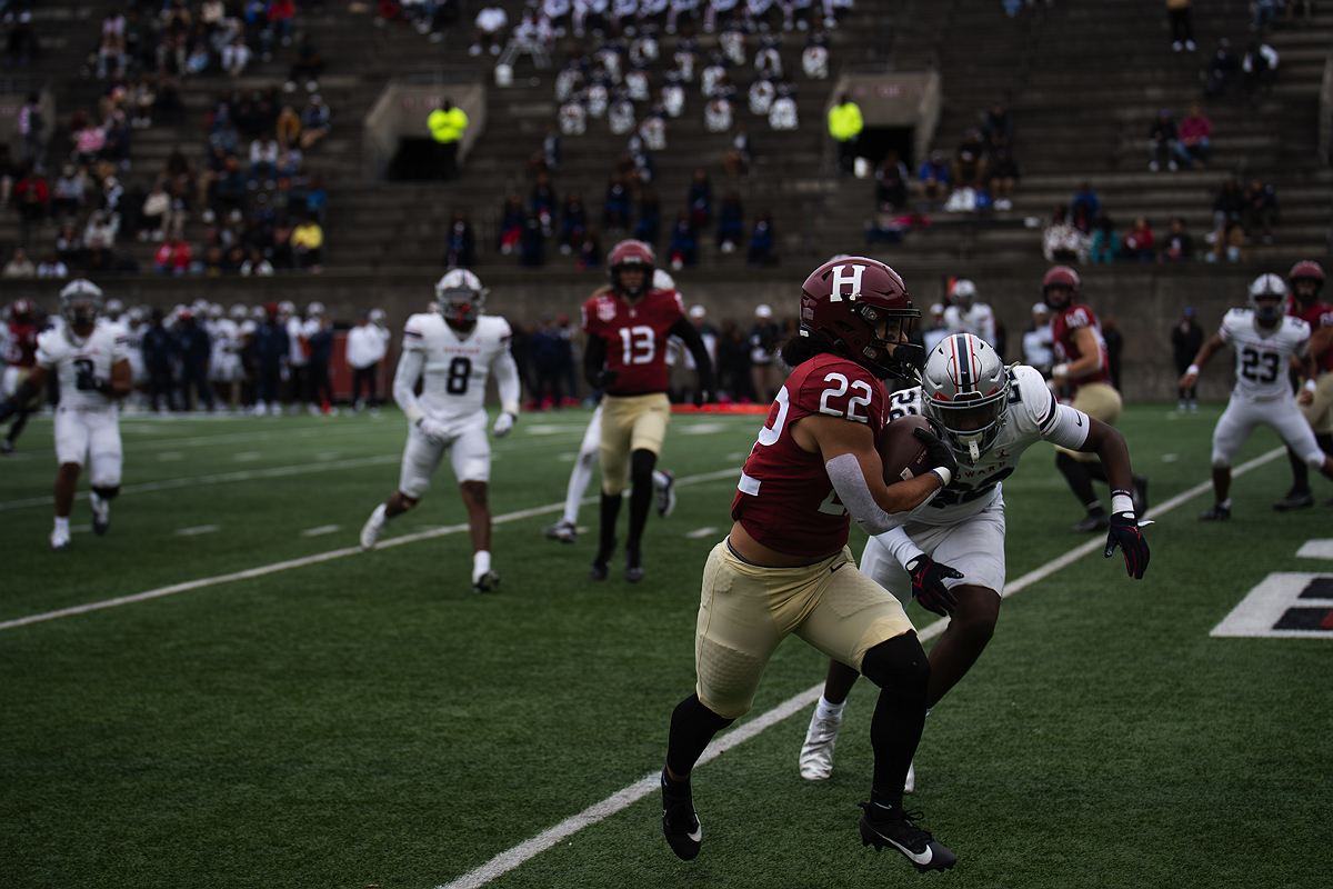Harvard player runs with ball as Howard player tries to tackle him