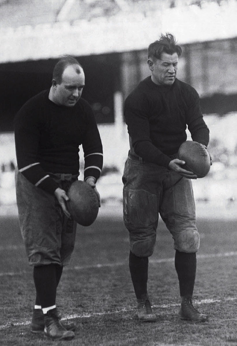 Charles Brickley and Jim Thorpe prepare to kick the footballs they are holding