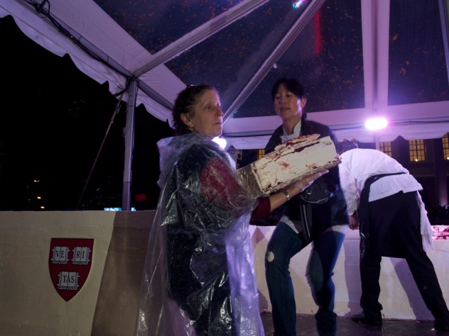 Photograph by Jim Harrison The moment the crowd has been waiting for: Joanne Chang ’91 begins to remove layered sheets from her massive red velvet cake so pieces can be cut and served.