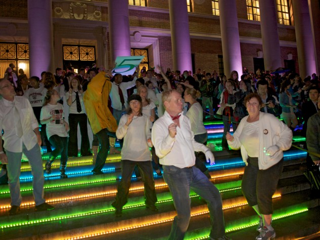 Photograph by Jim Harrison To get the evening's dancing started, a "flash mob" of dancers performed a choreographed routine they'd rehearsed throughout the previous week. The dancers were on the steps of Widener Library and at other Yard locations. Colorful LED lighting decorated buildings around the Yard.