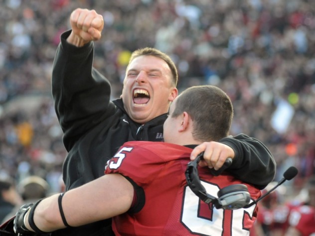Mark Kelsey / Harvard Crimson Defensive line coach Michael Horan and reserve tackle Adam Riegel ’13 share a jubilant hug after a 34-24 victory in The Game.