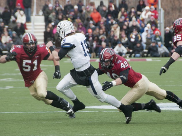 Photograph by Robert Worley As so often happened this season, an opposing quarterback—in this case, Yale’s Morgan Roberts—had nowhere to run against marauding Crimson defenders such as linebackers Jake Lindsey ’16 (number 51) and Eric Medes ’16 (number 49), who were helped by defensive tackle Miles McCollum ’17.