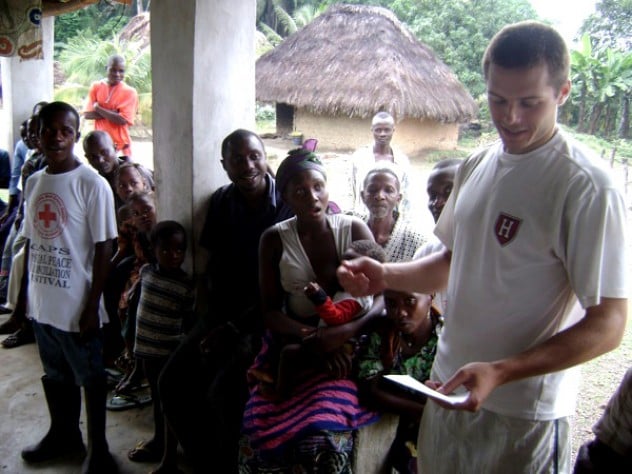 Courtesy of David Sengeh Using notes to bolster his command of Mende, the local language, Sam Slaughter ’09 introduces himself and the GMin team to villagers.