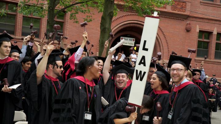 Harvard Law School graduates celebrate, gavels in hand.