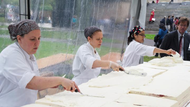 Workers start to apply the vanilla Swiss meringue buttercream frosting.