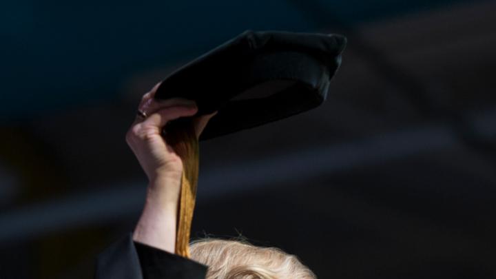 Clayton Spencer hoists the cap that her father, Samuel Reid Spencer, wore as president of Mary Baldwin College and of Davidson College, during her installation ceremony as the eighth president of Bates College. 