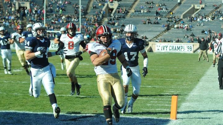 On Harvard’s first series, tailback Paul Stanton Jr. took a handoff from quarterback Conner Hempel, cut to the left sideline, and sprinted 25 yards for a touchdown. Stanton would score three more times in the opening half. Following him into the end zone are Yale defensive backs Robert Ries (34) and Spencer Rymiszewski (17), and Harvard wide receiver Andrew Berg (8). 