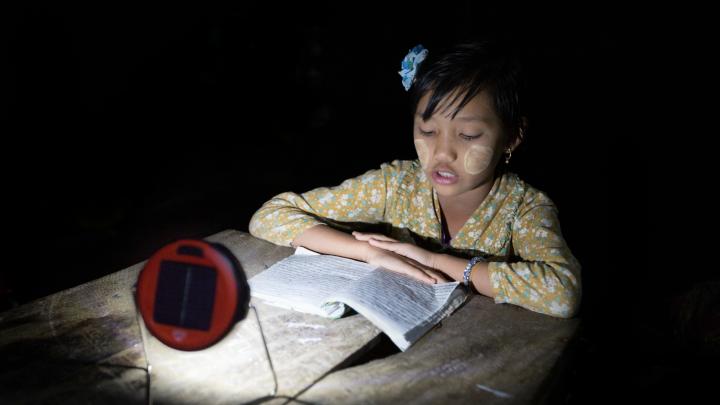 Proximity Designs now sells d.light solar lights—typically, on a multimonth installment plan. The basic light, shown here, has the most basic of uses: enabling reading, or homework, at night, in lieu of candles, which are expensive, a fire hazard in bamboo houses, and unsuitable for use under mosquito netting. (The white paste on the girl’s cheeks is <i>thanaka,</i> a cosmetic paste made from ground bark, which many women and girls in Myanmar apply to guard against sunburn and to protect the skin.)