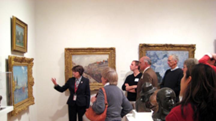 Docent Susan Glassman describes a painting to a group of guests