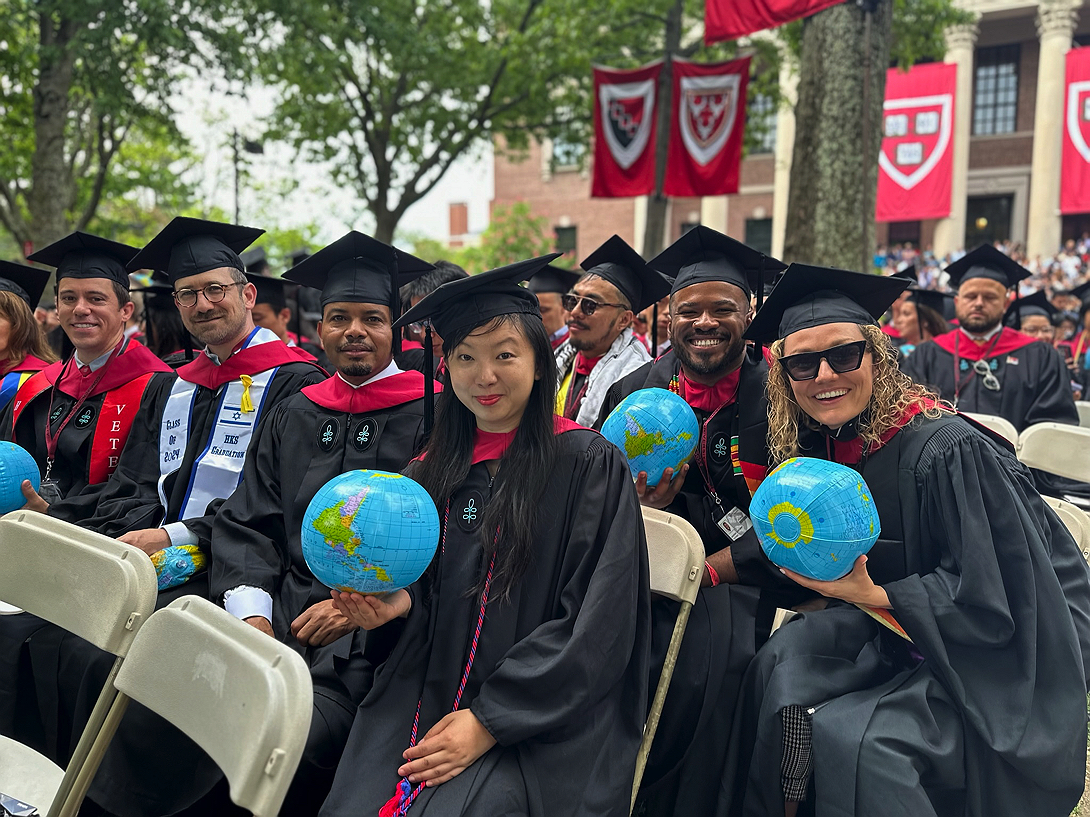 Harvard Kennedy School graduates holding globe beach balls