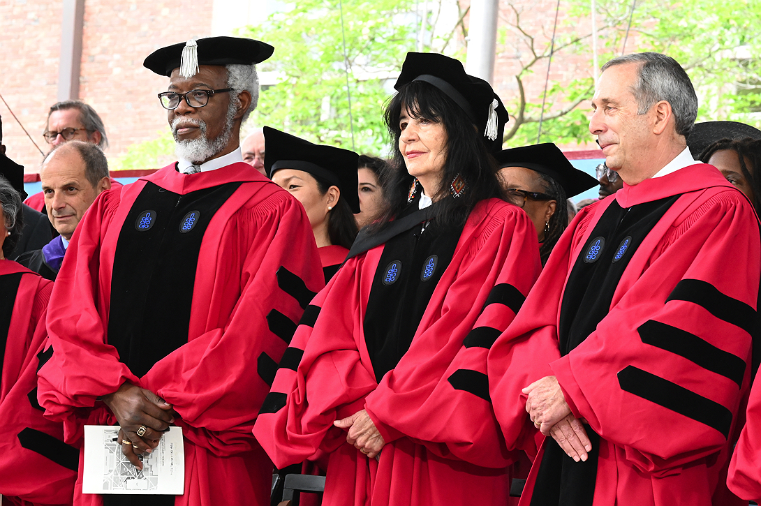three people wearing red academic robes standing 