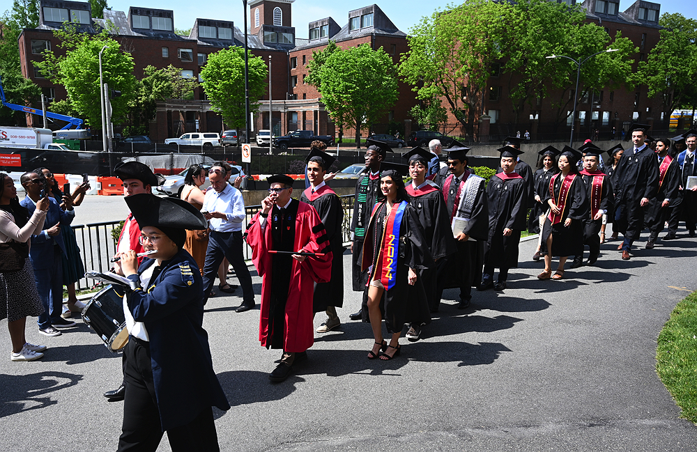 graduates in black caps and gowns processing to Sanders Theater
