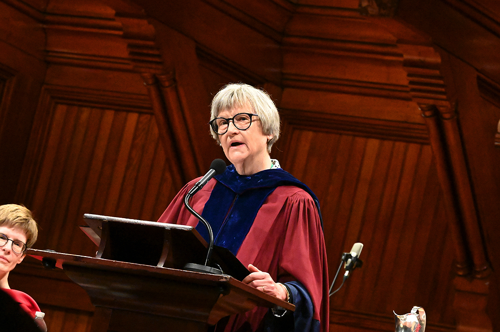 Drew Gilpin Faust, wearing a red robe, addresses audience at Sanders Theater