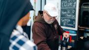 A friar serves drinks at a food truck labeled "Capuchin Mobile Ministries."