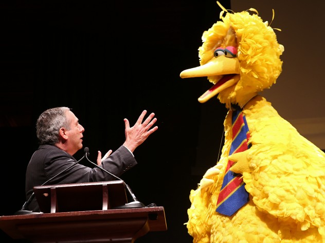 President Bacow and Big Bird talking on stage
