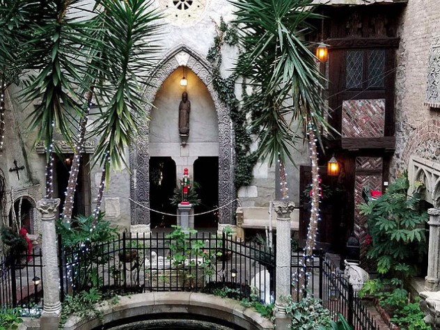 Photo of the cloister courtyard decorated for the holidays with strings of lights and touches of red amid the greenery