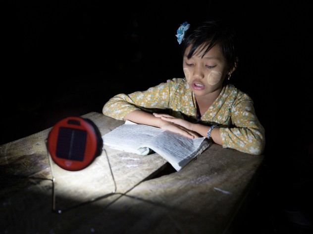 Photograph © Tim Mitzman for Proximity Designs 2013 Proximity Designs now sells d.light solar lights—typically, on a multimonth installment plan. The basic light, shown here, has the most basic of uses: enabling reading, or homework, at night, in lieu of candles, which are expensive, a fire hazard in bamboo houses, and unsuitable for use under mosquito netting. (The white paste on the girl’s cheeks is <i>thanaka,</i> a cosmetic paste made from ground bark, which many women and girls in Myanmar apply to guard against sunburn and to protect the skin.)