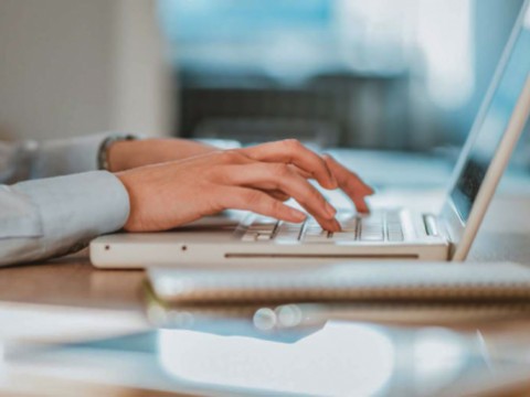 Hands typing on a computer keyboard.