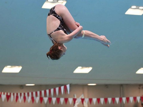 Georgina Milne flies through the air, flipping toward the water.