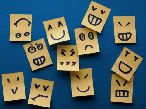 Multiple small paper tabs, each decorated with a simple line drawing of a different facial expression