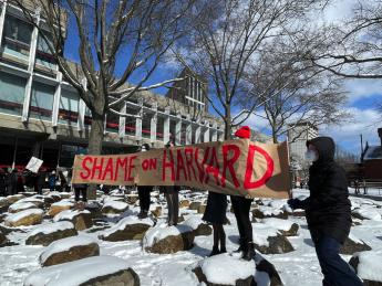 Demonstrators hold up a sign that reads, "Shame on Harvard." 