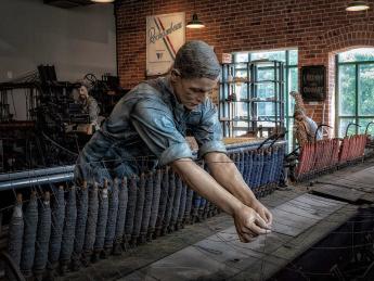 A replica of a textile mill shows life-like statues of workers. 