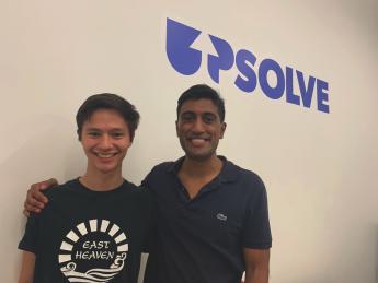 Upsolve co-founder Rohan Pavuluri (right) and summer staffer Nick Brown in front of an Upsolve sign.