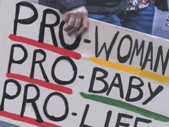 An activist holding a poster: "Pro-Woman, Pro-Baby, Pro-Life."