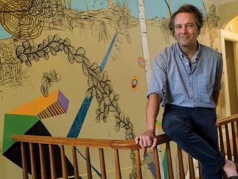 Dan Chiasson at home in front of a “sometimes delightful, sometimes disturbing” mural by David Teng Olsen, which appears in The Math Campers.