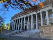 The facade of Widener Library with columns and steps with blue sky and trees