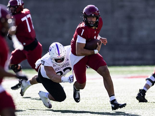 Holy Cross player attempts to tackle Harvard player 1 who is running with ball