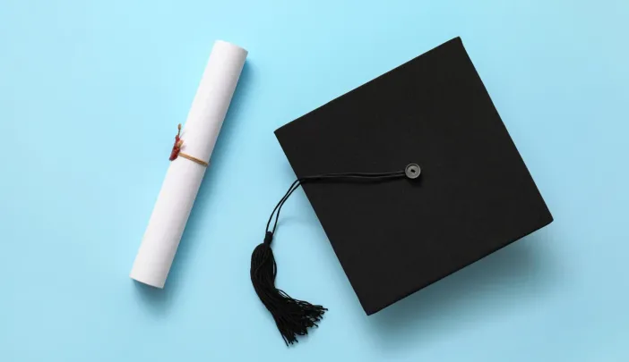 Graduation hat and diploma on color background