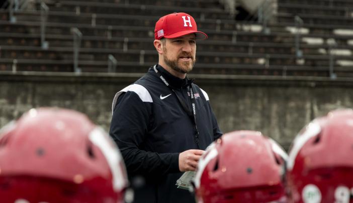 Coach Andrew Aurich standing in the center among a crowd of football players in the foreground