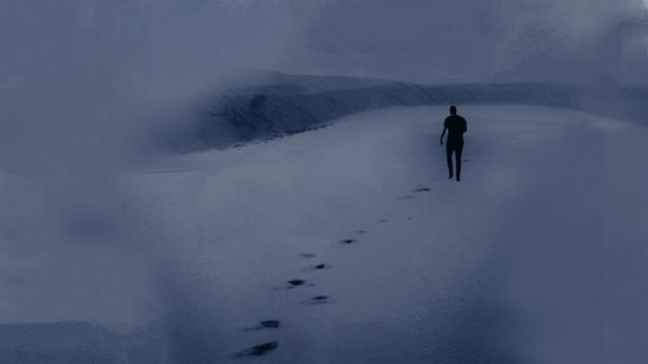 Person walking alone in a vast, empty desert at night, leaving a trail of footprints behind. 