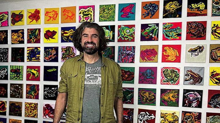 Bradley Scott Davis standing in front of a wall of frog paintings