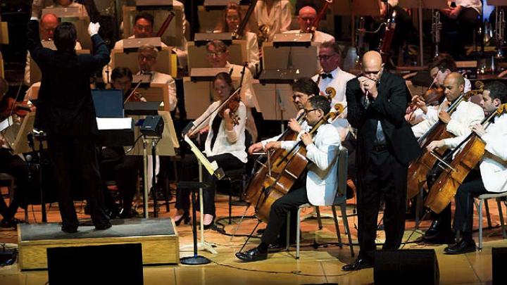 Johnson plays his harmonica with the Boston Pops orchestra behind him.