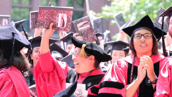 Graduate School of Education degree recipients wave composition books, to be donated to local schools