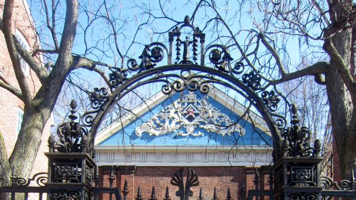 The arch of the delicate Class of 1870 Gate acts like a raised eyebrow, perfectly framing a view of Holden Chapel's ornate blue gable. The gate has been locked for decades, preventing pedestrians along Massachusetts Avenue from entering the chapel's intimate courtyard.