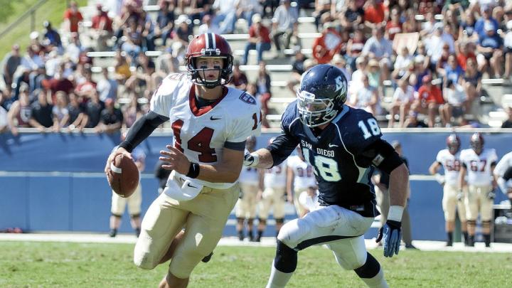 Conner Hempel (14), making his first start at quarterback, threw four touchdown passes as Harvard opened the season with a victory over the University of San Diego. The pursuing defender is end Blake Oliaro. 