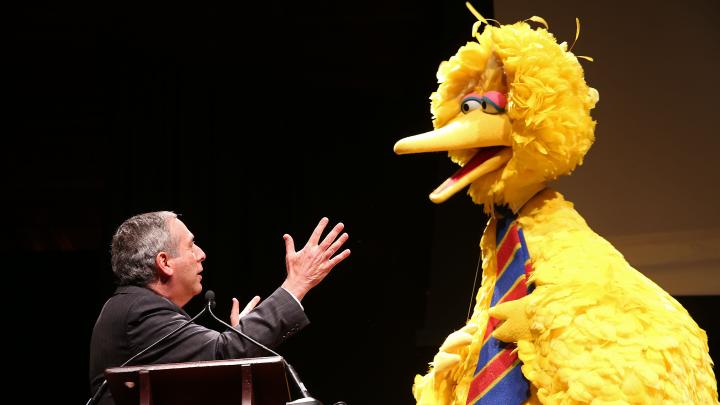President Bacow and Big Bird talking on stage