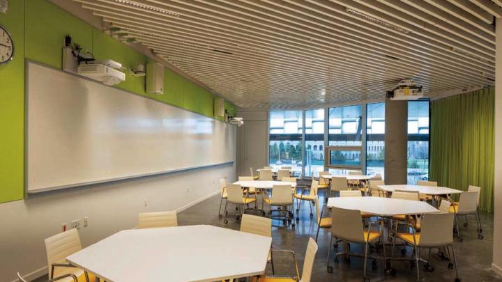 One of various flexible classrooms, filled with white hexagonal tables and bright yellow chairs